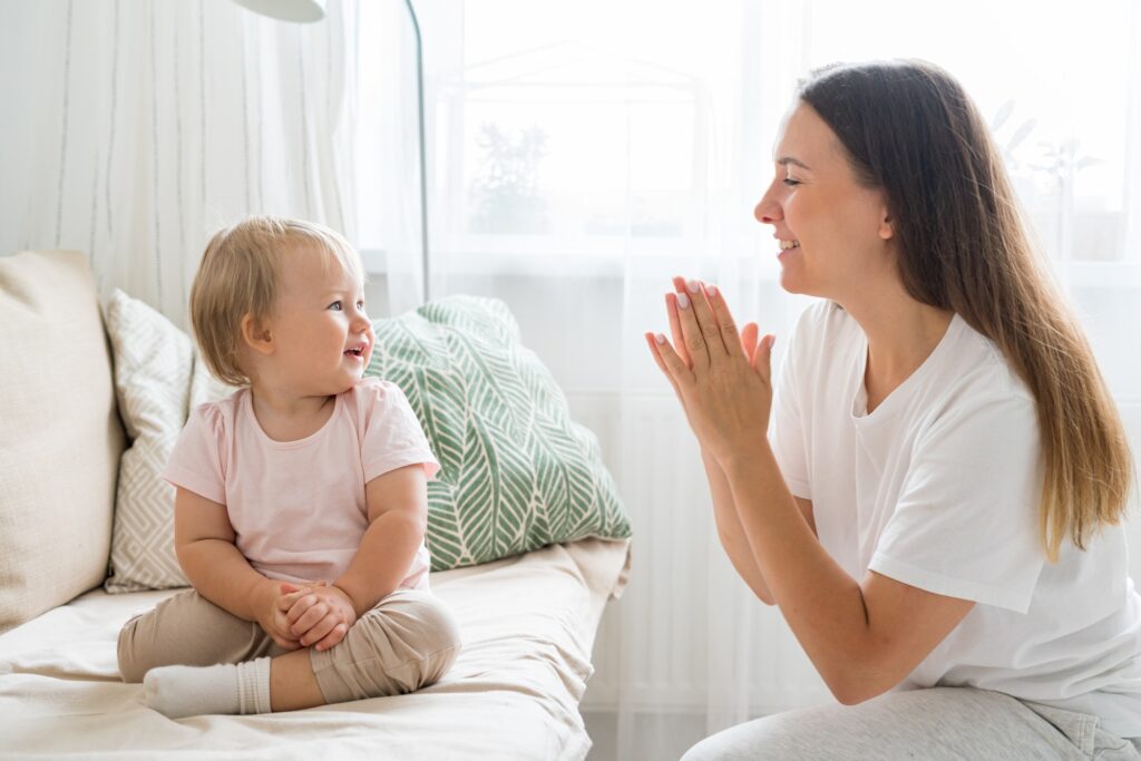 Smiling mother encouraging happy toddler at home image supporting KeyWord family care content
